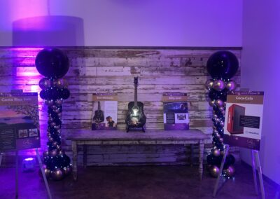 A dimly lit room adorned with purple lighting and colorful balloons, creating a festive and vibrant atmosphere.